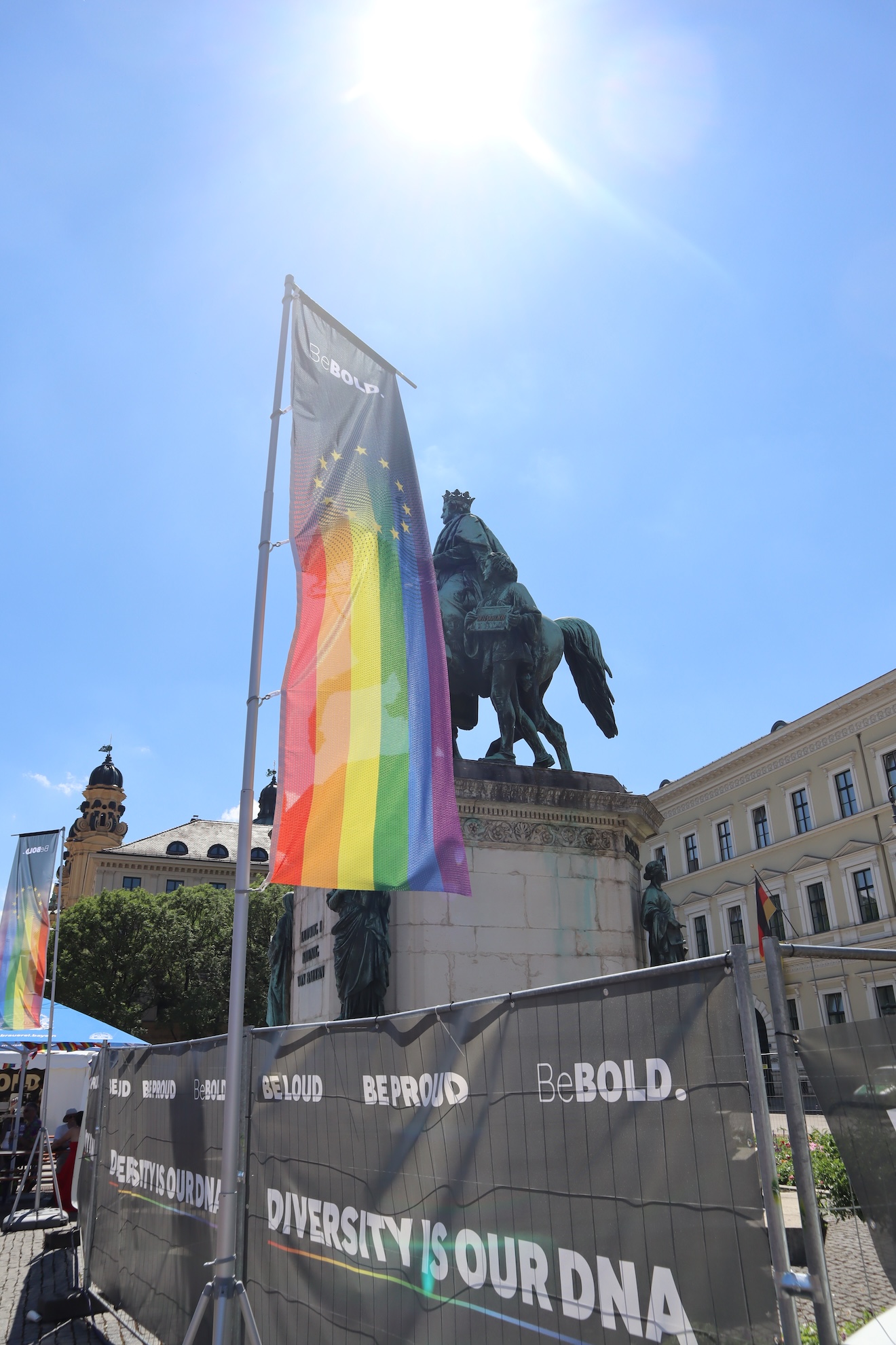 CSD München - eine Pride Fahne vor Reiter Statue und blauer Himmel